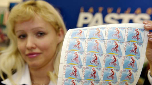 A post worker shows the first Latvian stamps denominated in both lats and euros in Riga on January 30, 2013.
